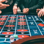 close up view of a roulette table with a few people's hands